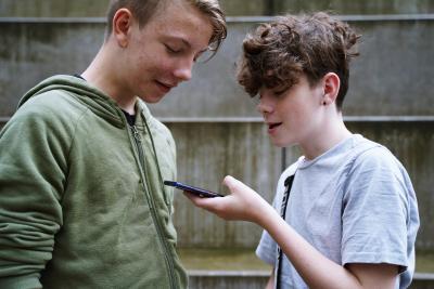 To skoleelever kigger ned på en telefon