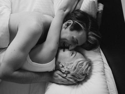 Par i sengen griner og kysser