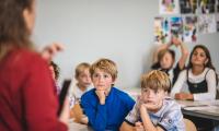 En skoleklasse sidder og lytter til en lærer