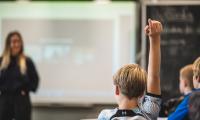 En skoleelev rækker hånden op i en undervisningstime