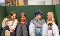 Fire skoleelever sidder på en bænk