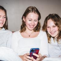Tre skoleelever kigger på en telefon