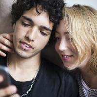 Ungt par læser om sexsygdomme på telefon